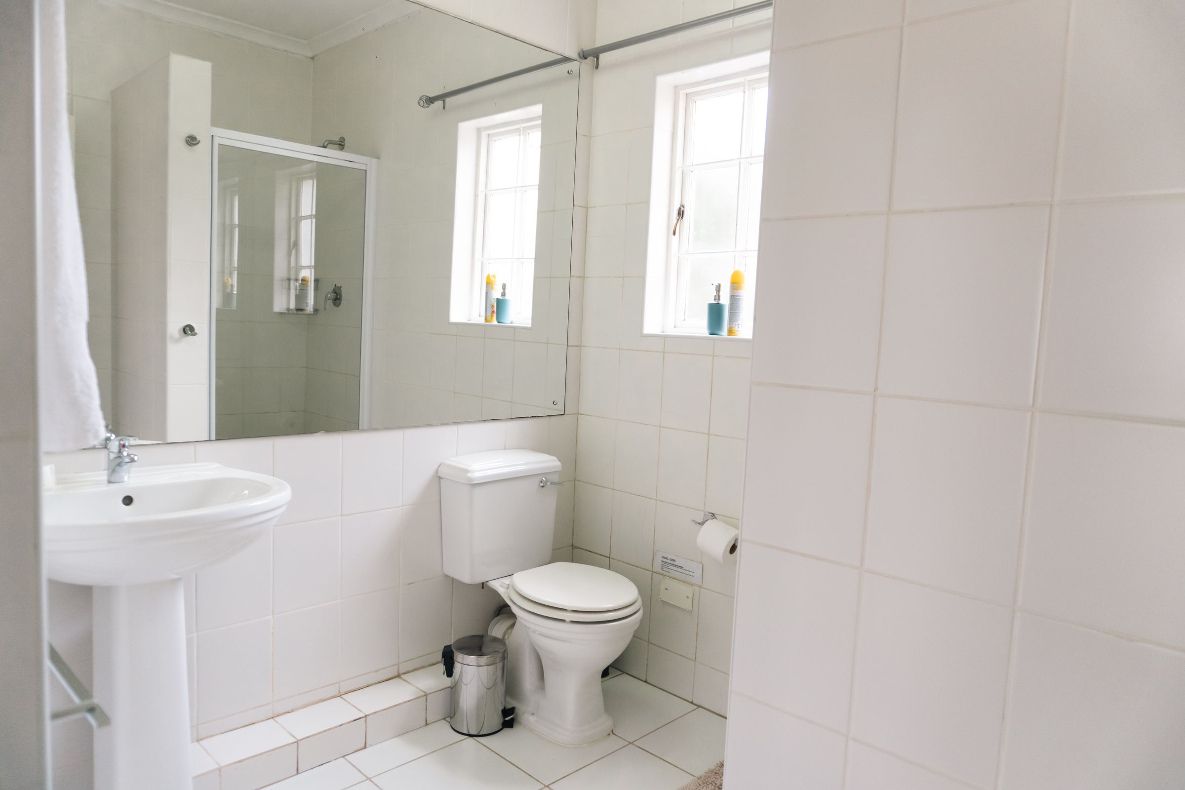 A white bathroom with a shower, a basin and a long mirror