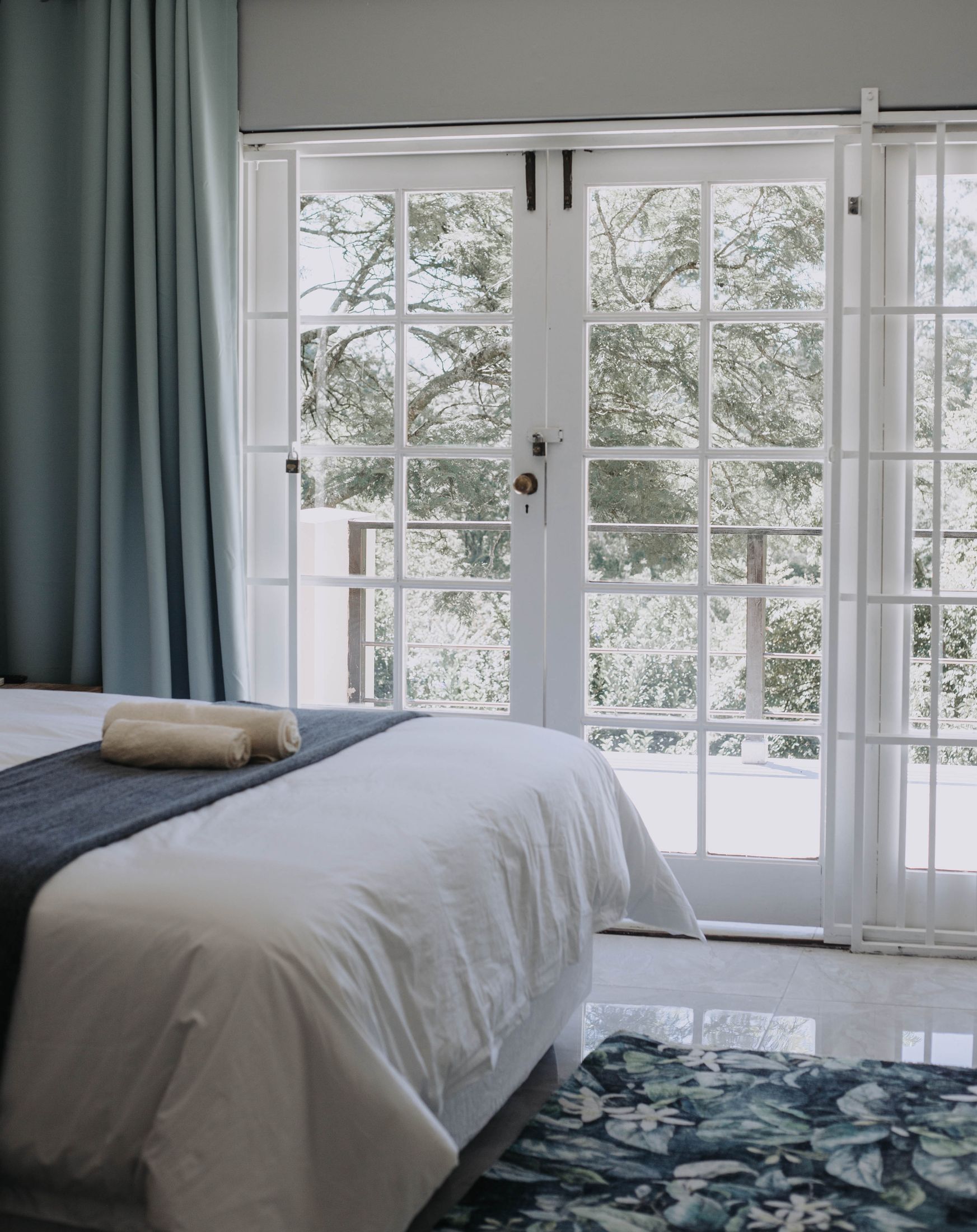 A bed facing French doors that open onto the trees