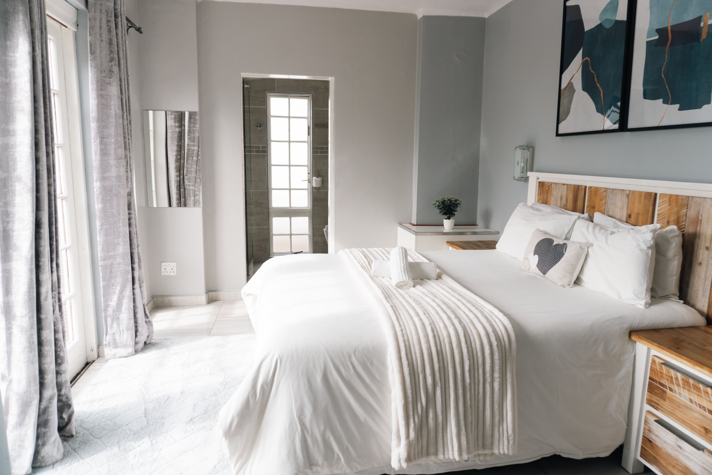 A bedroom with long grey curtains and a glass door to the garden