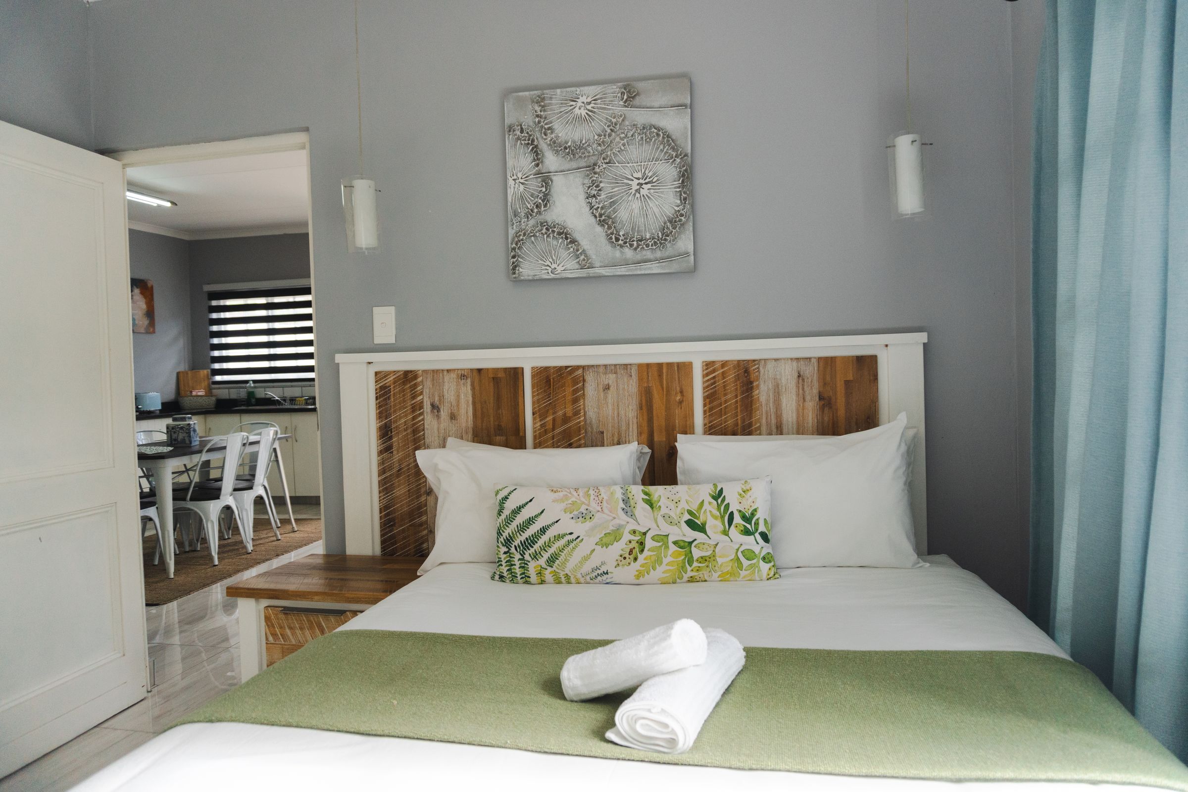 A bed with a green throw and a door through to the dining room