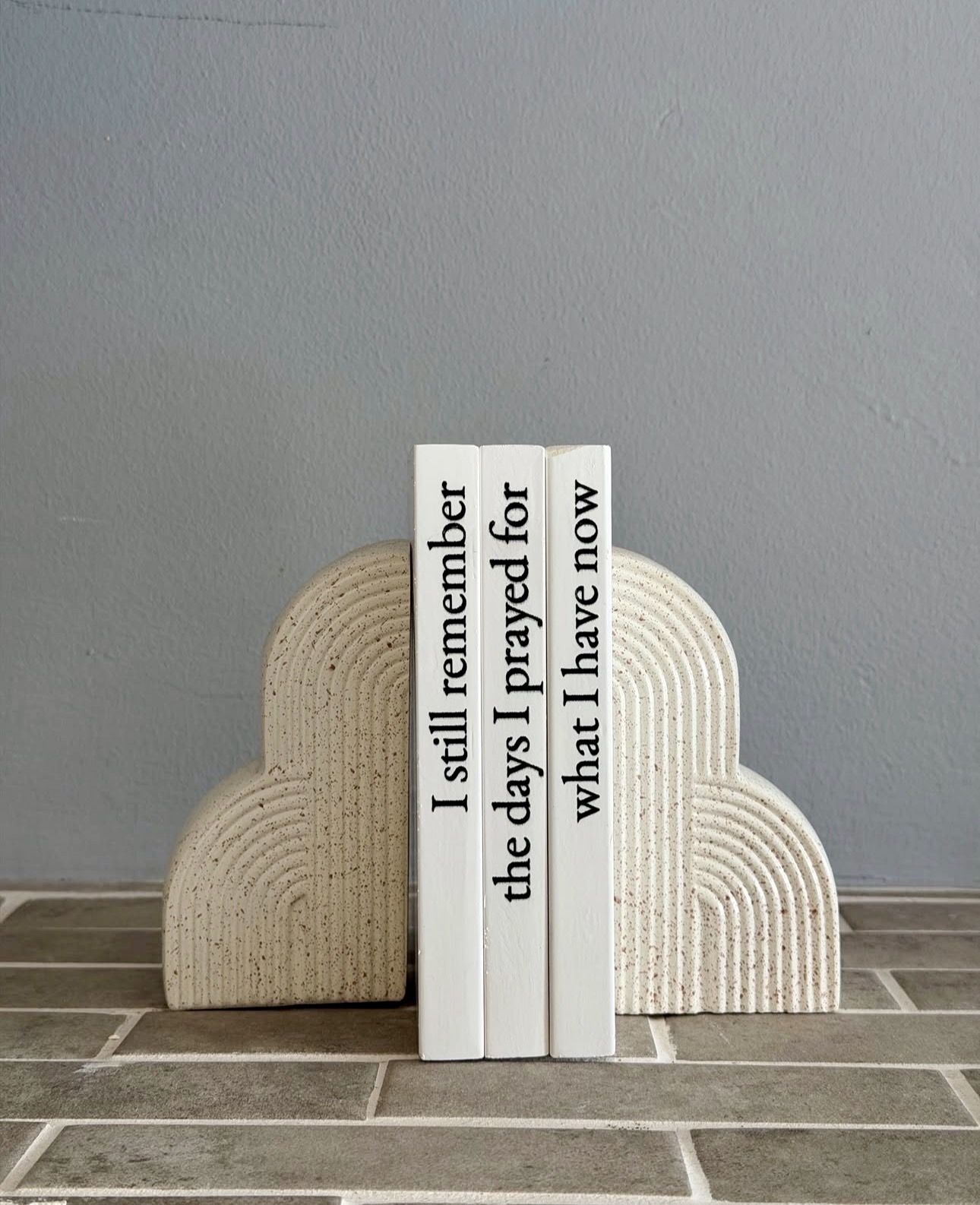 Three white books standing in an arch shaped bookend