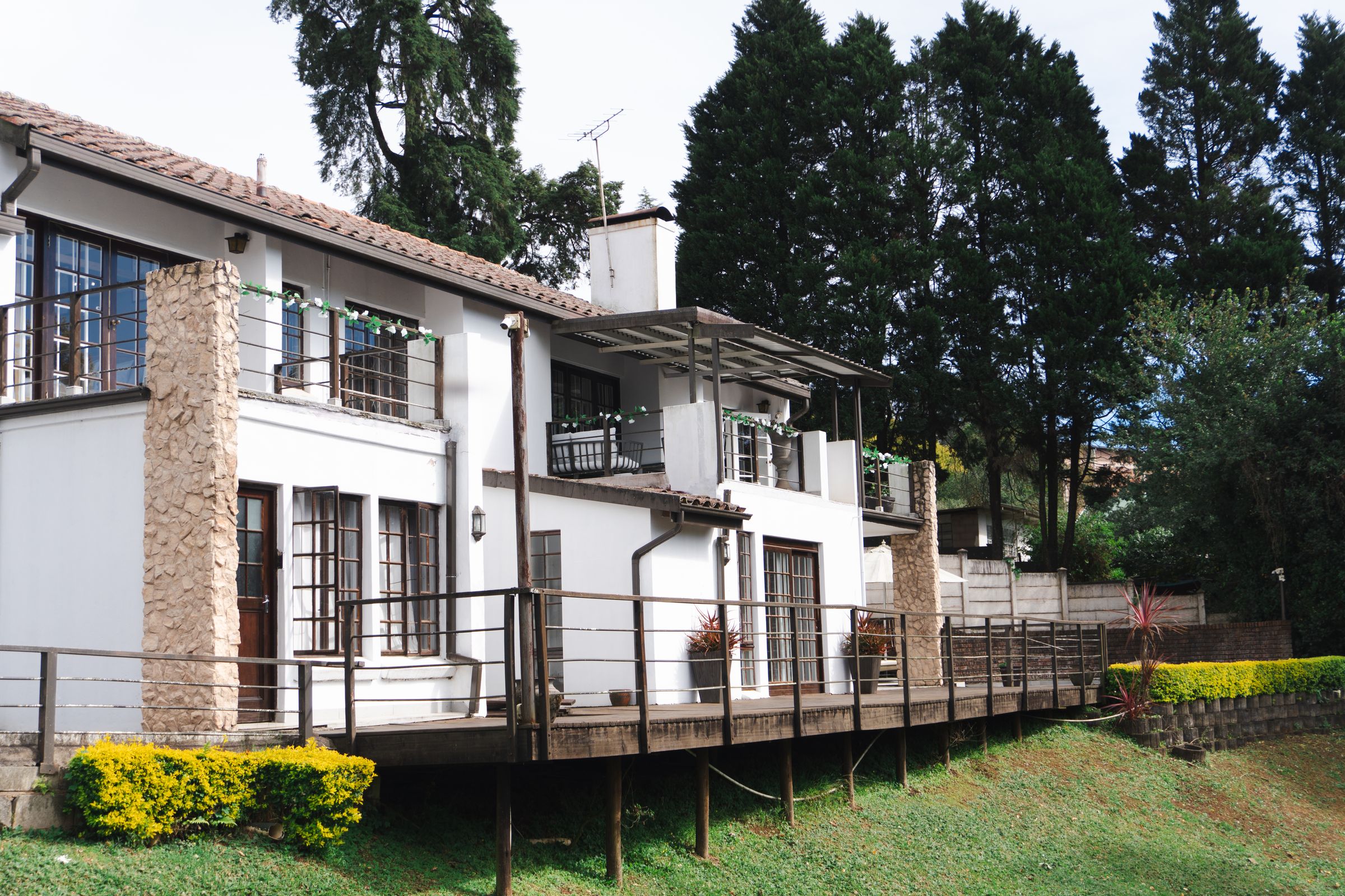 The double storey villa at 9 Azalea Drive, with a stone chimney and a long timber deck