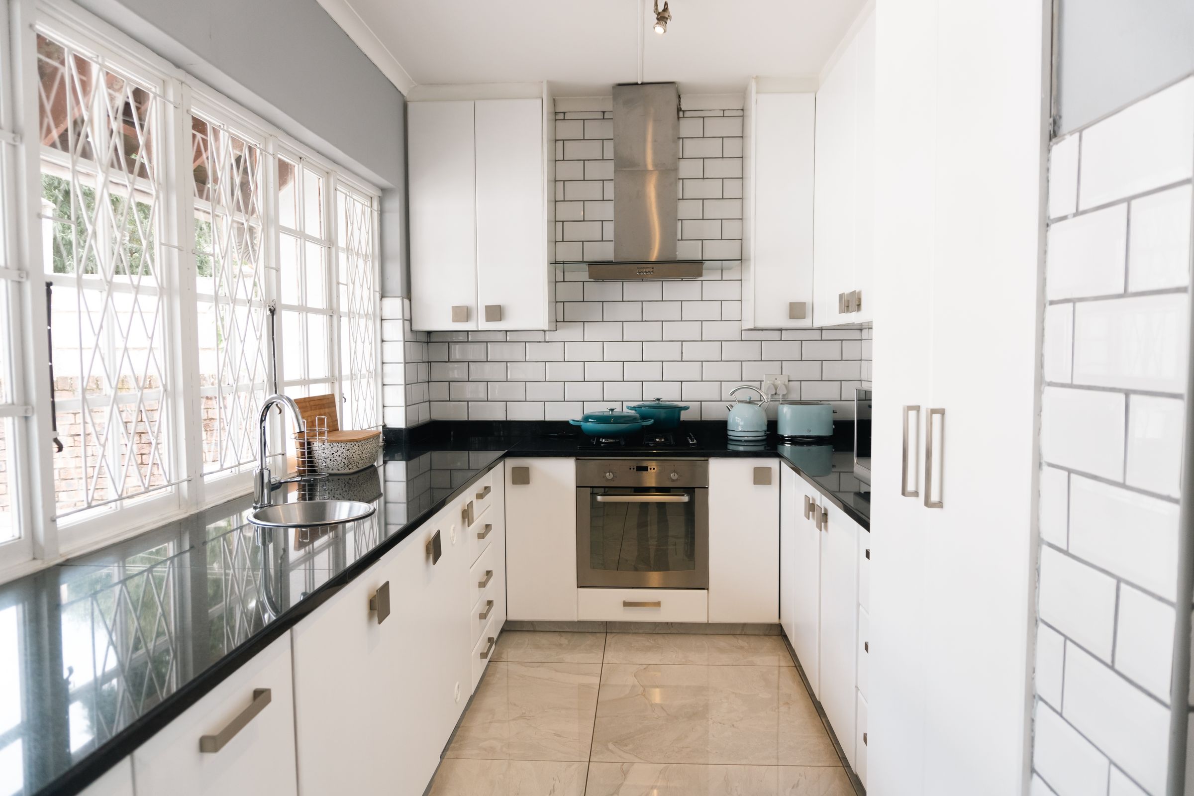 The white kitchen with subway tiles, a black counter and an oven