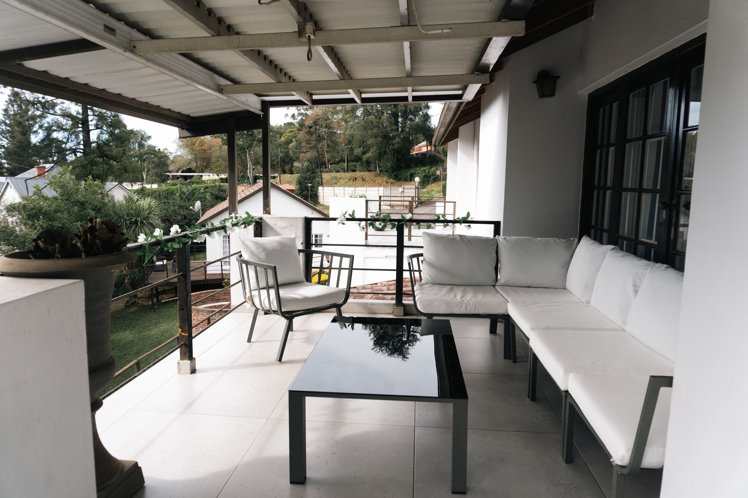 The covered patio with a white corner couch and a glass table
