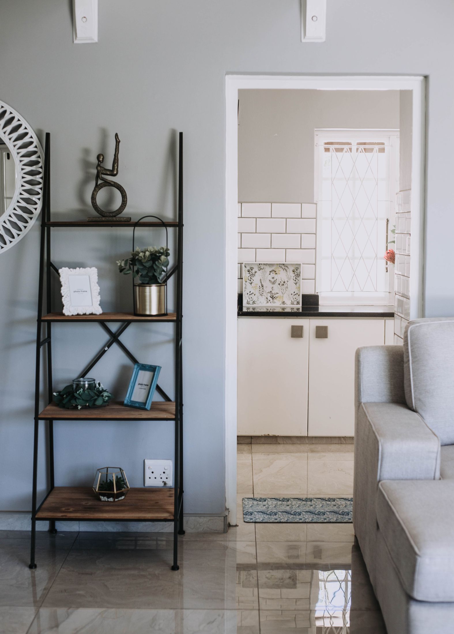 A shelf of plants and books beside the door to the kitchen