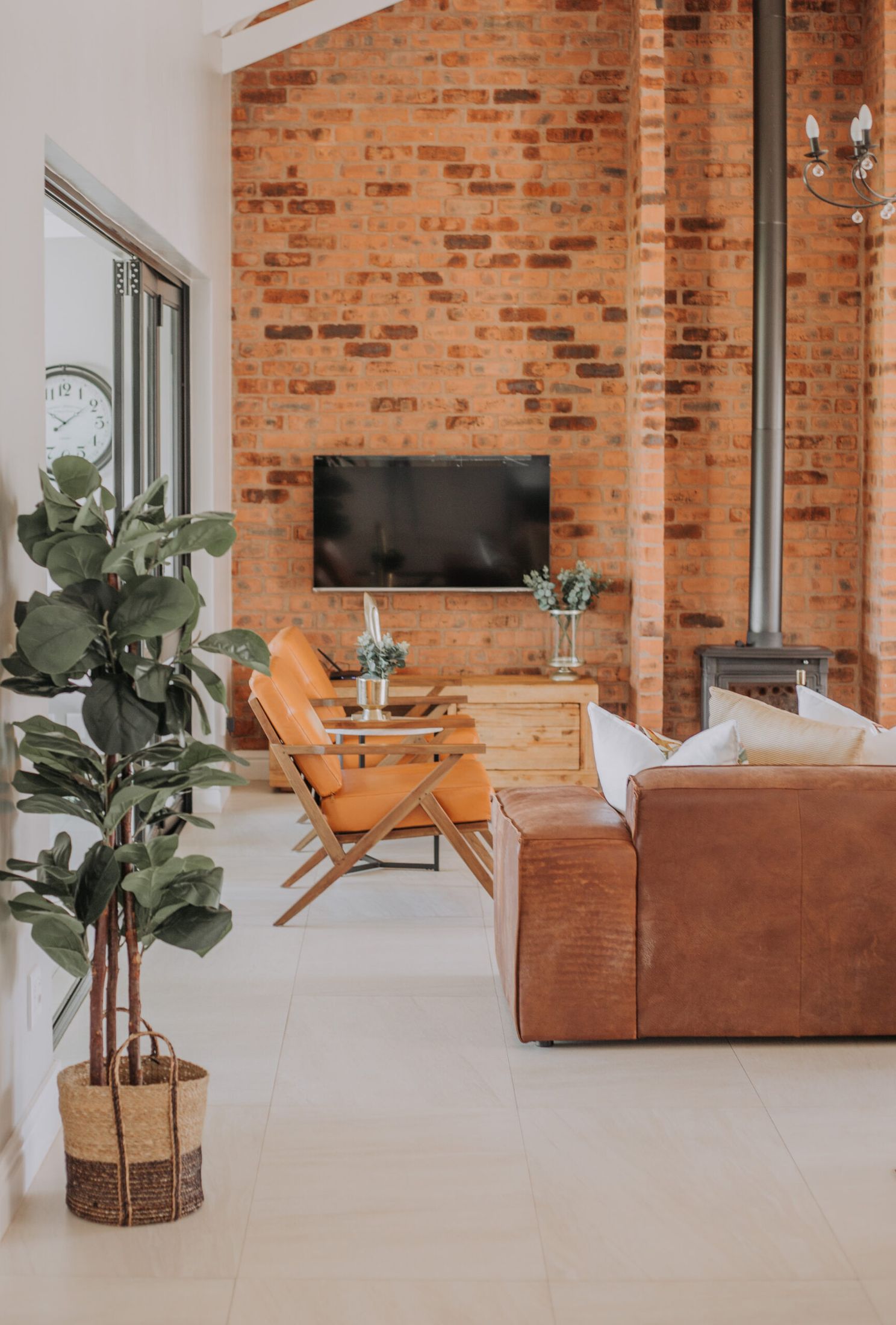The double volume lounge at Garlington, with a brick chimney wall and a tan leather couch