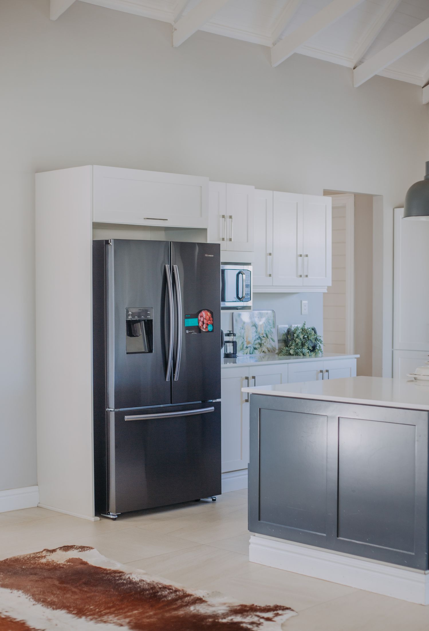 The kitchen with a black double door fridge and white cupboards