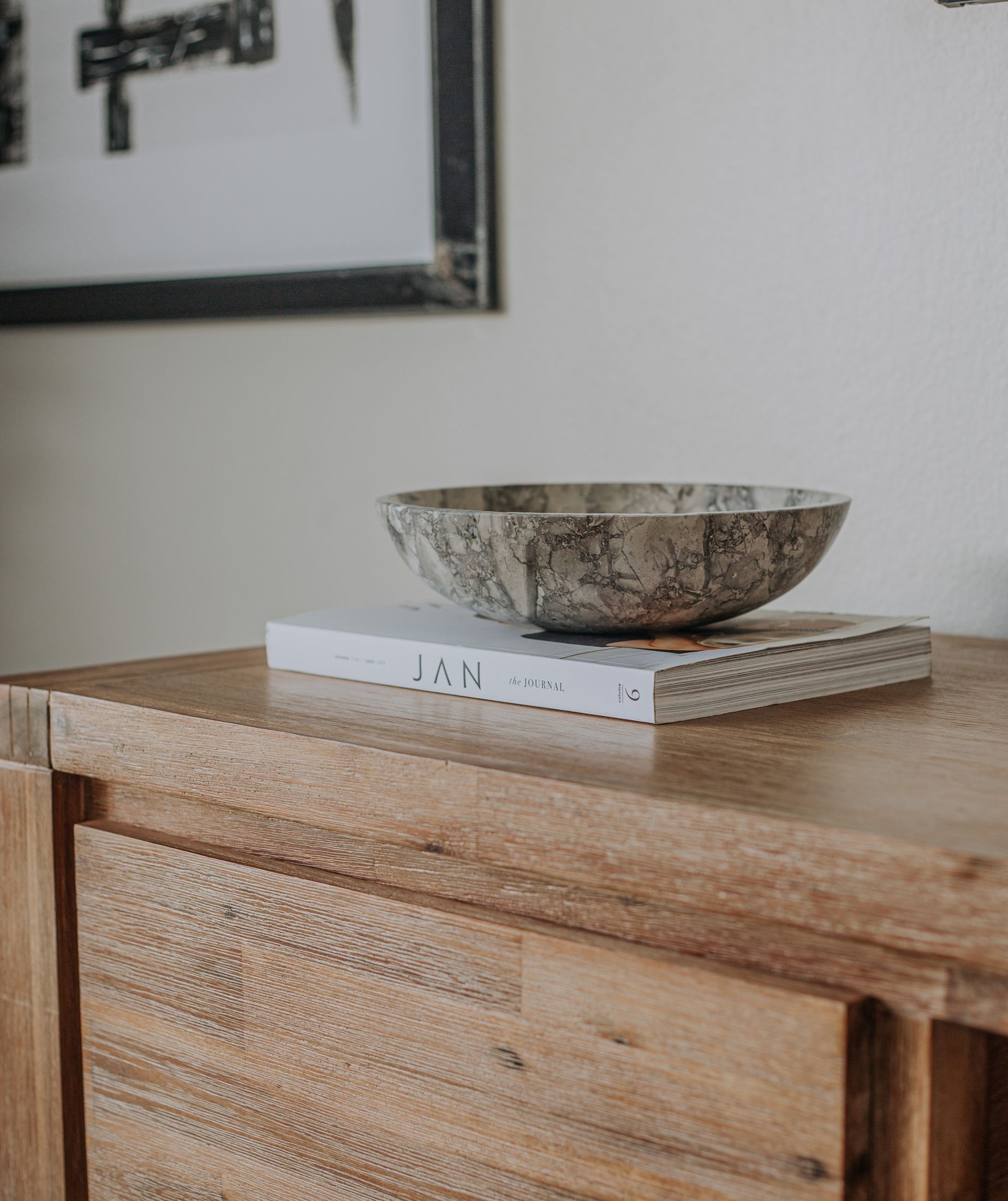 A stone bowl on books on a timber sideboard