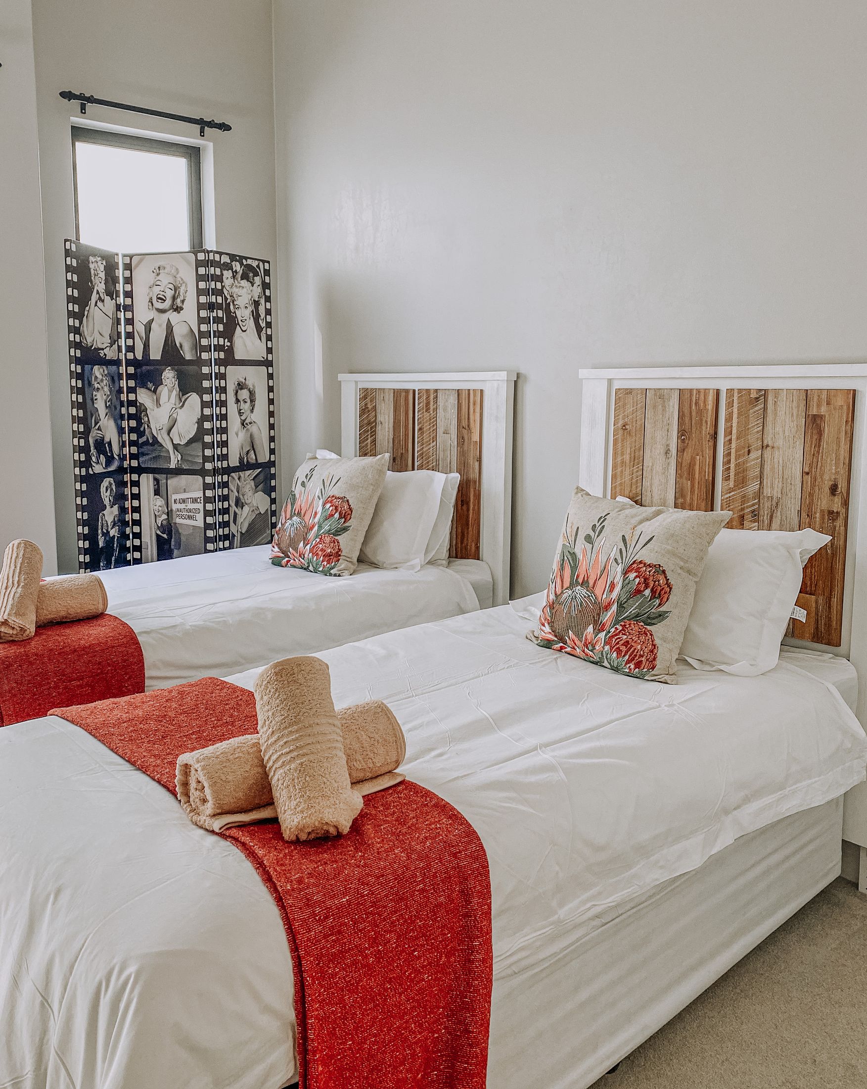 Two single beds with timber headboards and red throws
