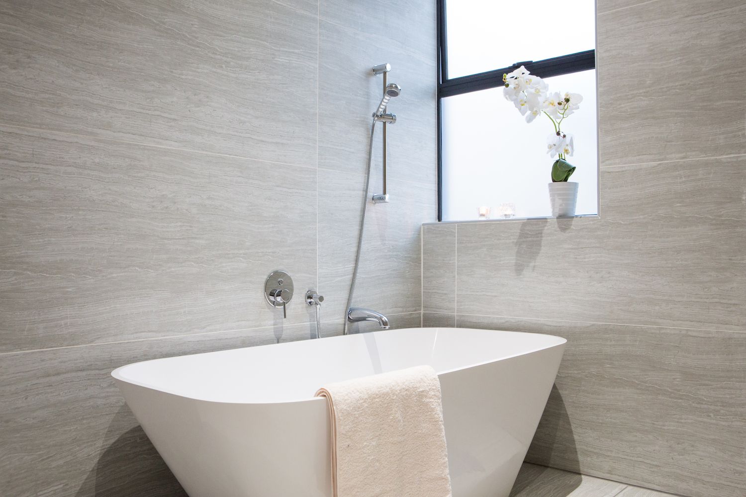 A freestanding bath under a window in a Unit 5 bathroom
