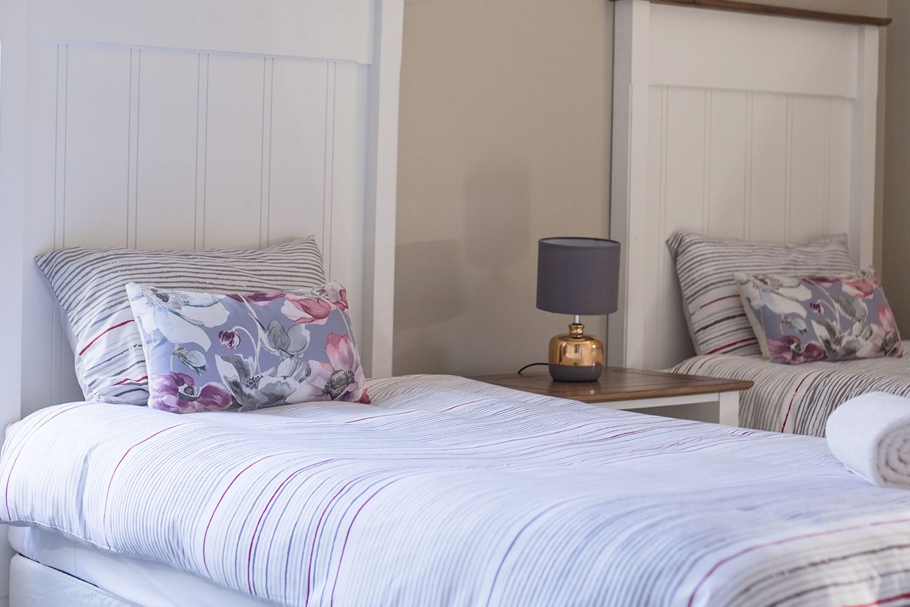A bed with floral cushions under a sloped white ceiling