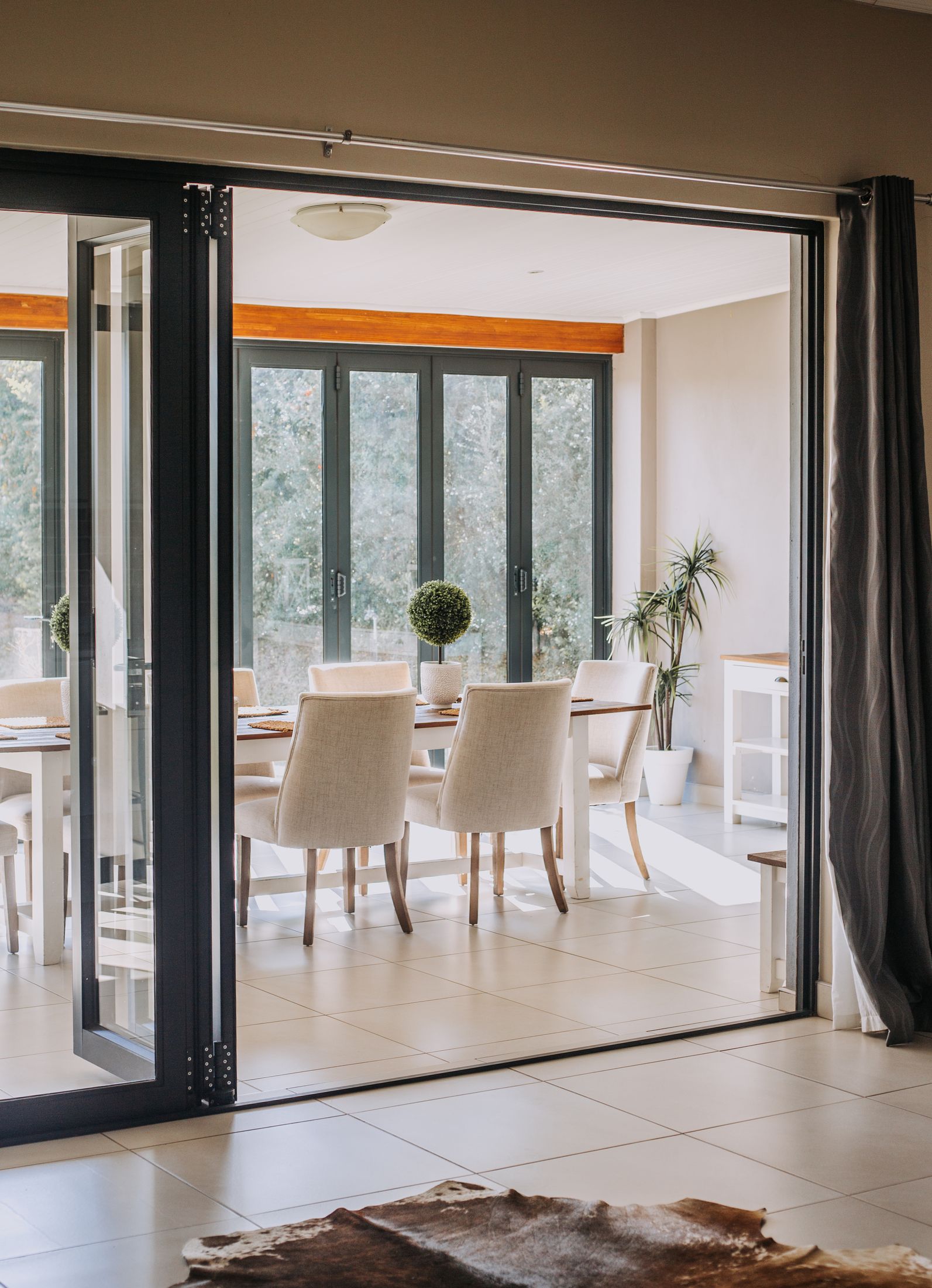 The dining room seen through open glass doors, with folding doors to the garden behind