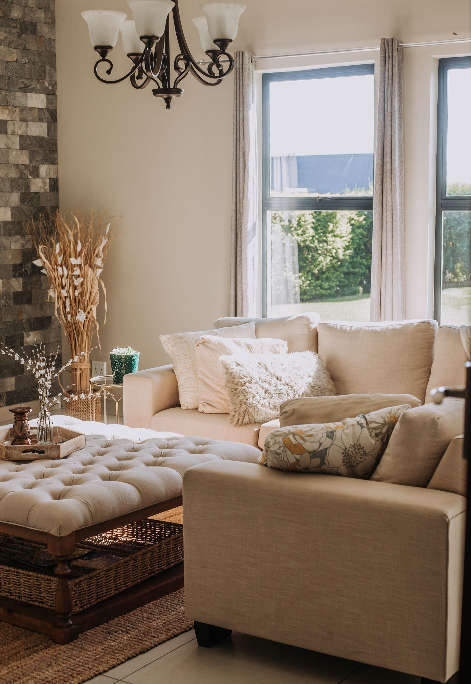 Cream couches and a buttoned ottoman by the window in Unit 5