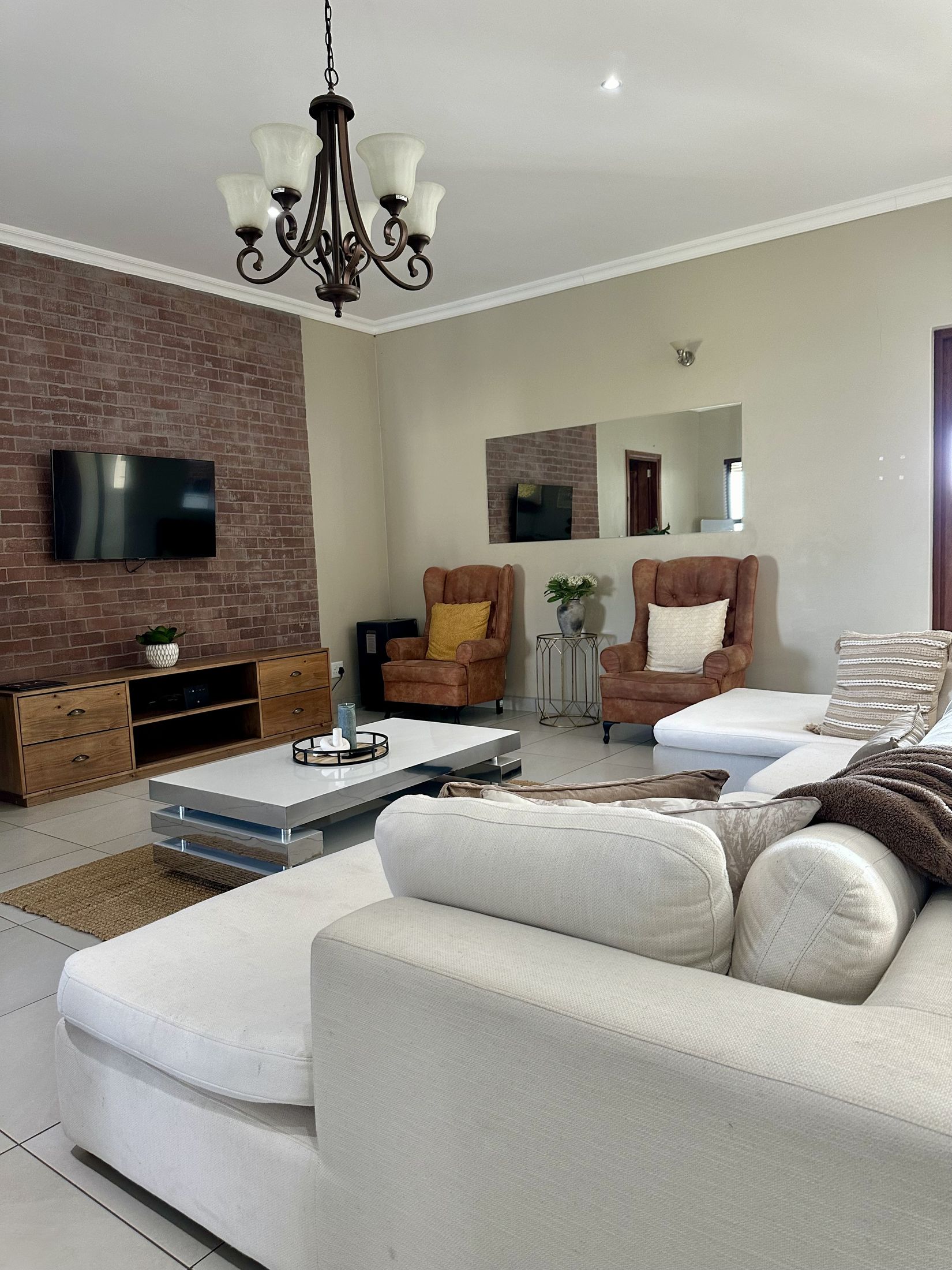 The Unit 5 lounge with white couches, a brick wall and a chandelier