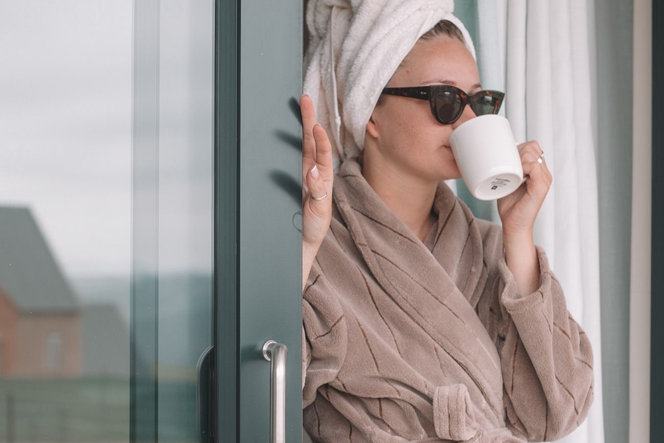 A guest in a gown drinking coffee at the glass door