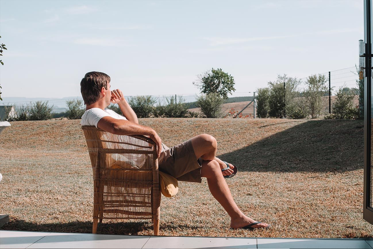 A guest sitting in the sun on the patio, looking out over the estate