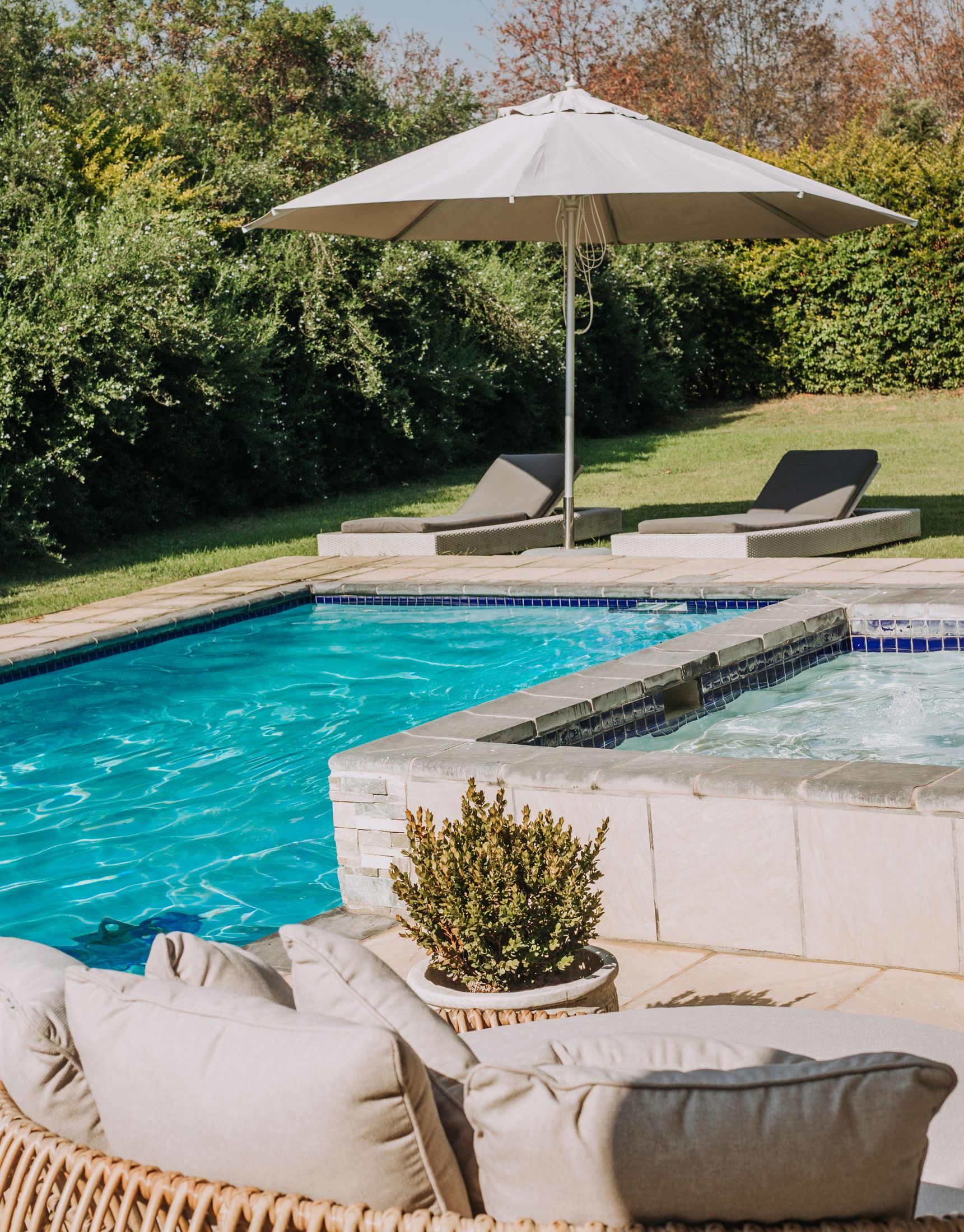 The Unit 5 pool with loungers and a white umbrella on the lawn