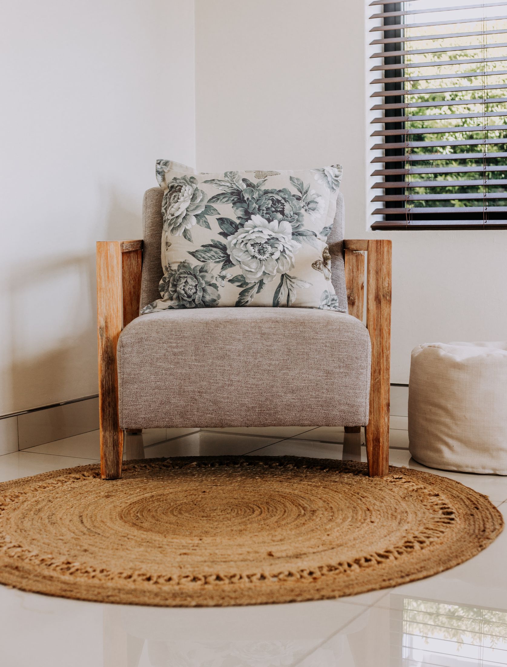 An armchair with a floral cushion on a round jute rug