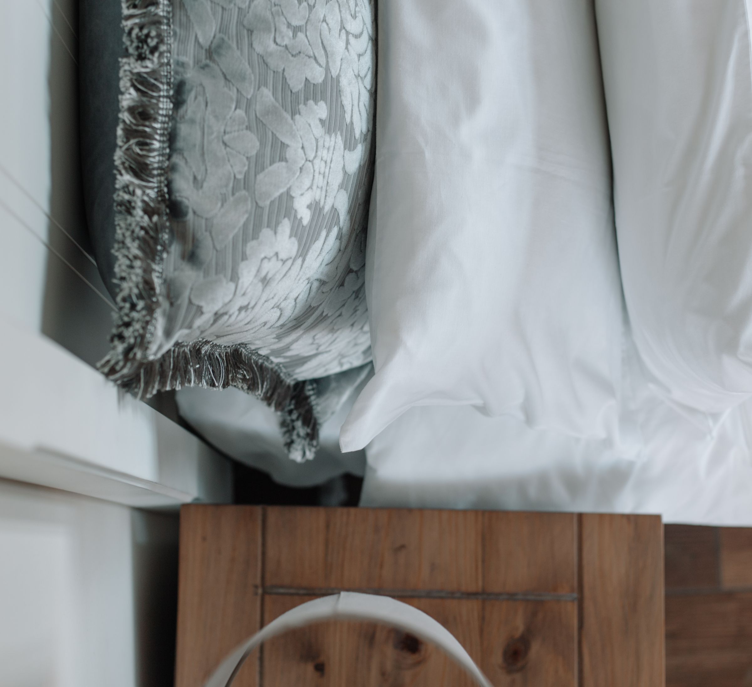 Grey and white linen folded over the foot of a bed