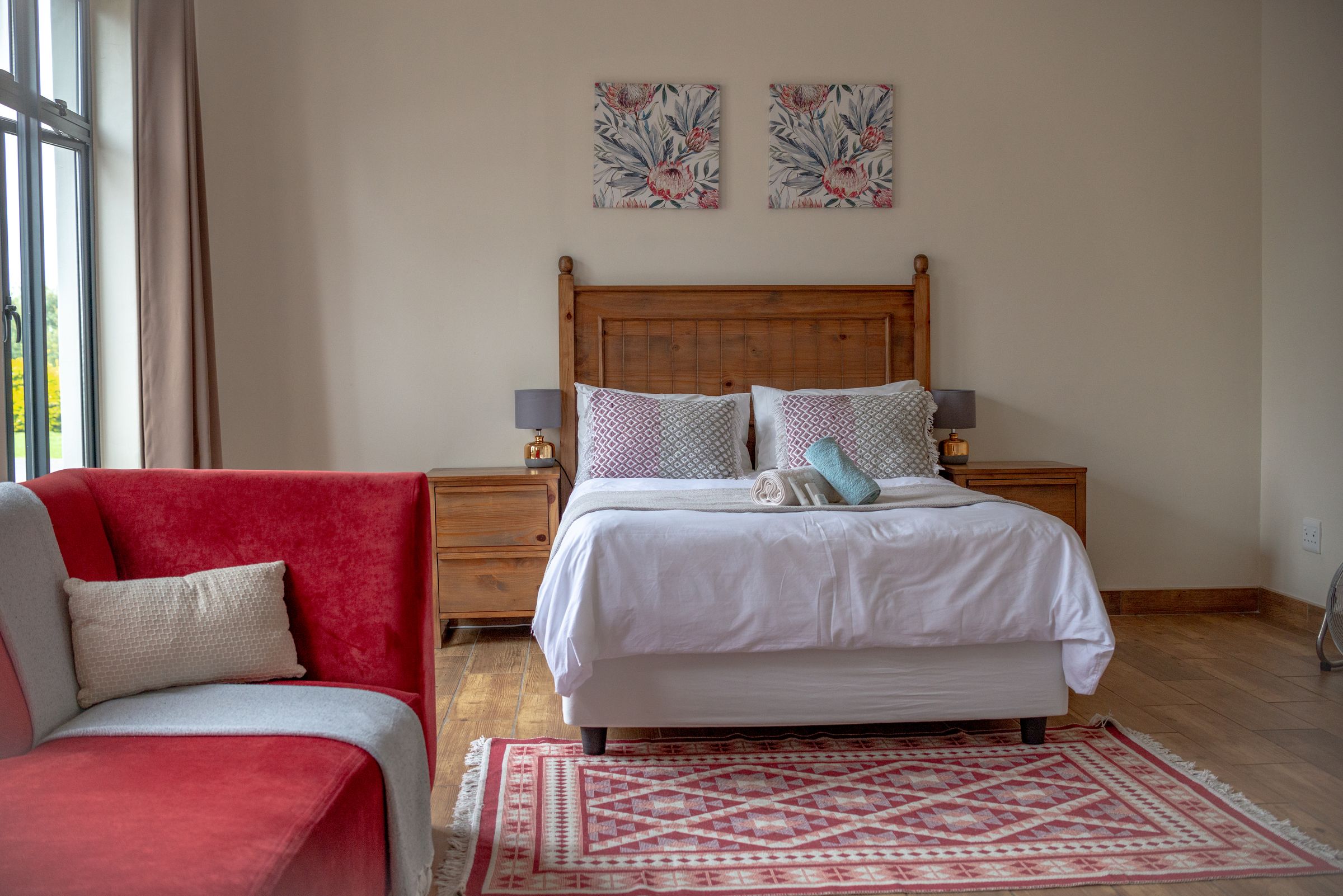 A Unit 6 bedroom with a timber bed, a red armchair and a patterned rug