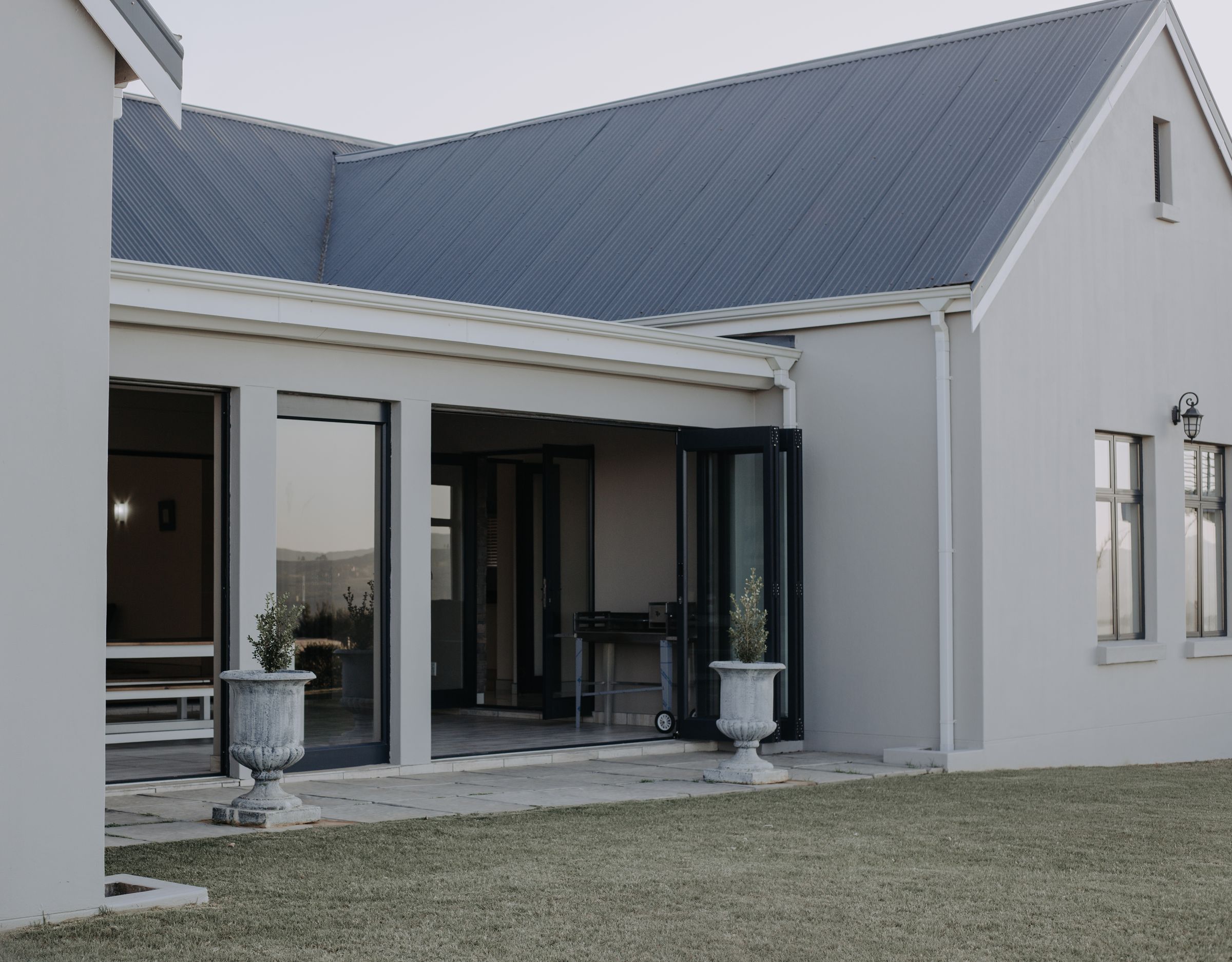 The back of Unit 6, with a covered patio and folding glass doors onto the lawn
