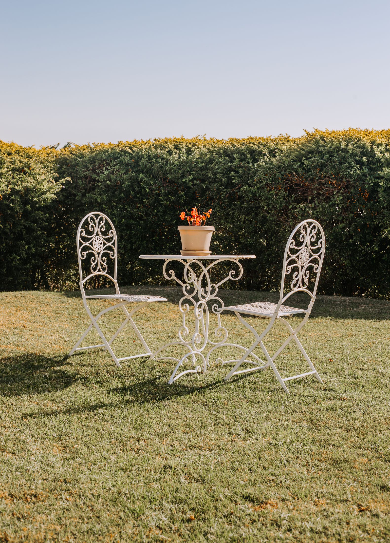 A white iron table and two chairs on the lawn