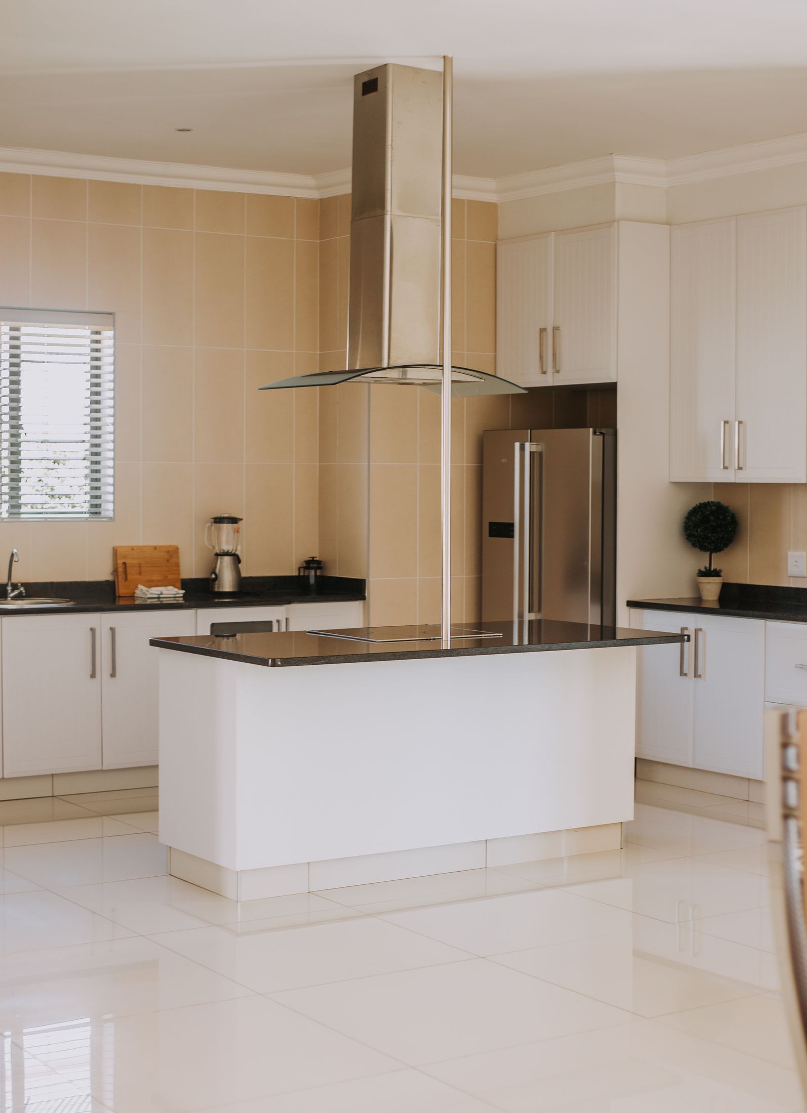 The Unit 6 kitchen with an island, a steel extractor hood and a double door fridge