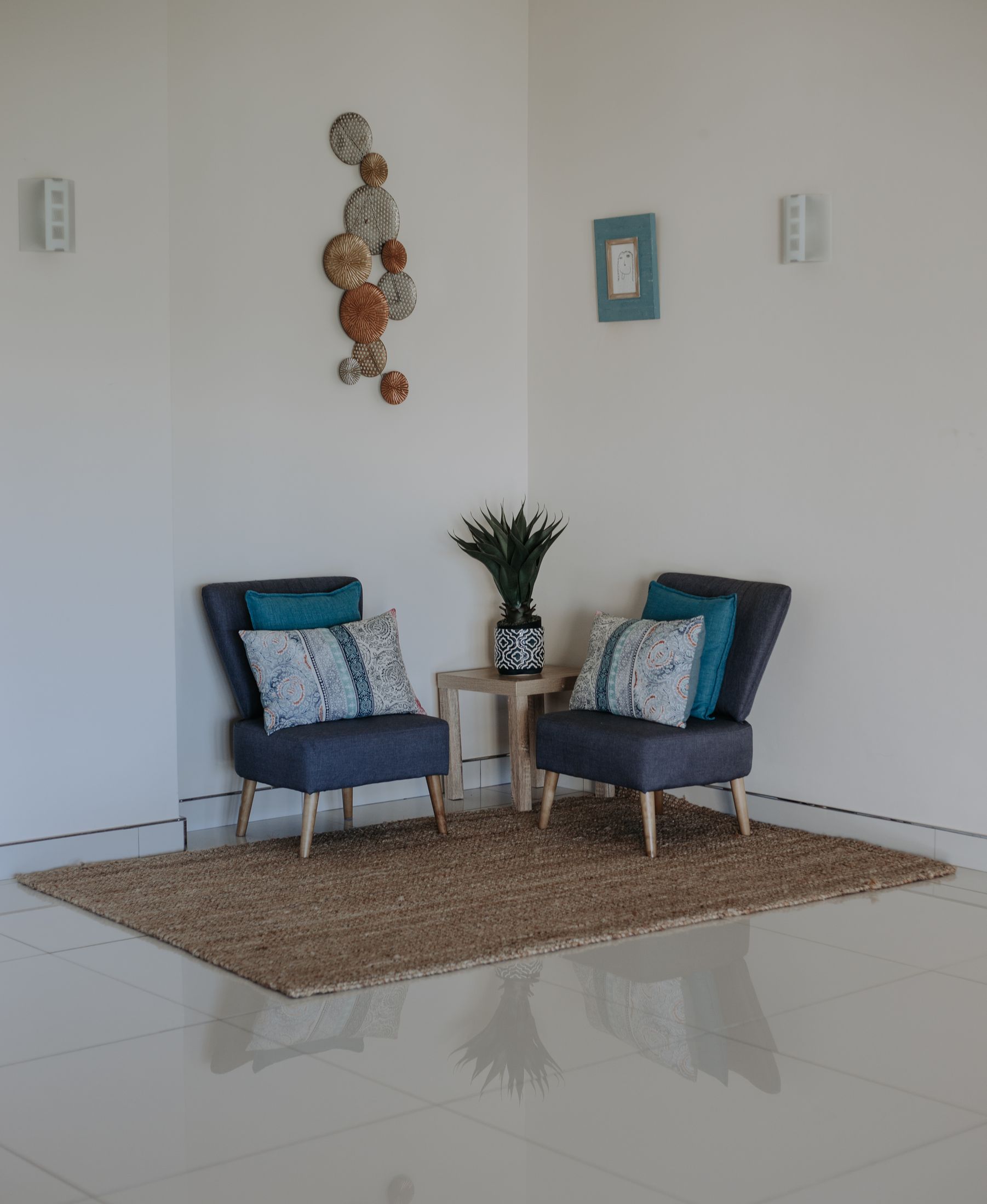 Two navy armchairs in a corner of Unit 6, with woven plates on the wall