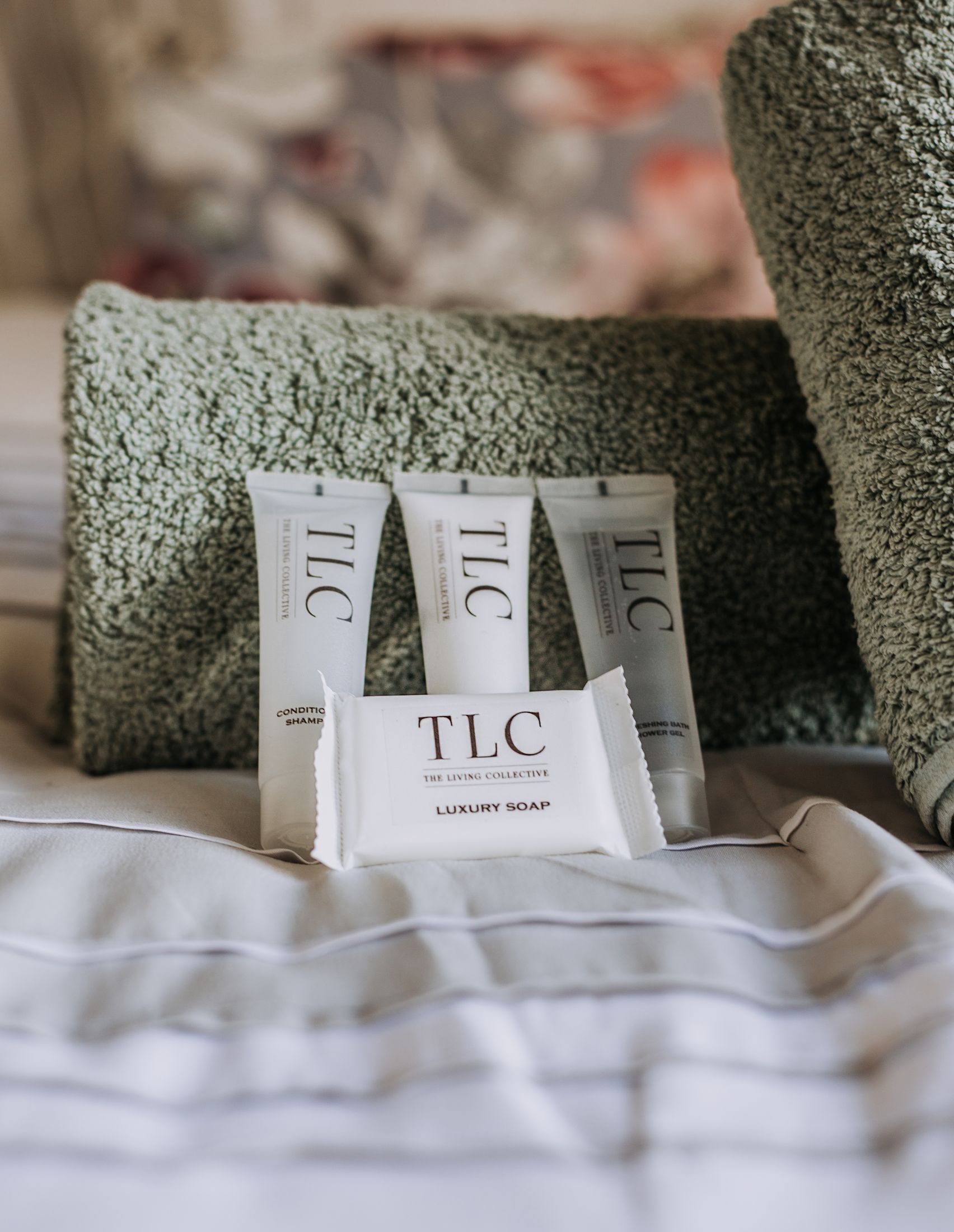 TLC toiletries and a soap set out on a made bed