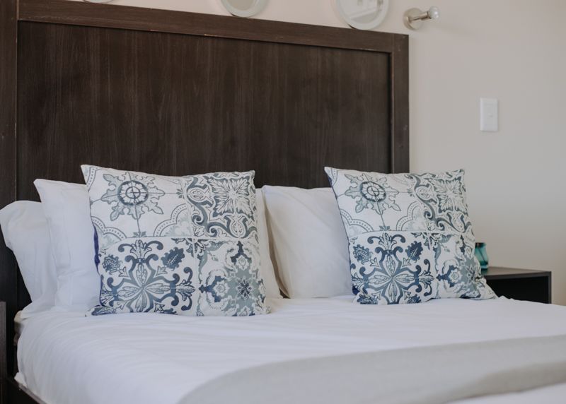 A double bed with blue patterned cushions and a dark headboard