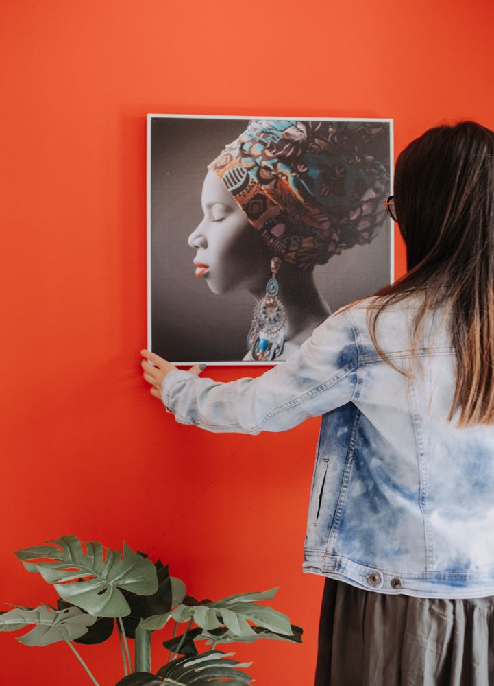A guest hanging a portrait on an orange wall