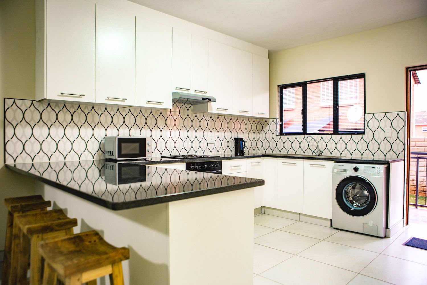 A long stay kitchen with a breakfast bar, stools and a washing machine