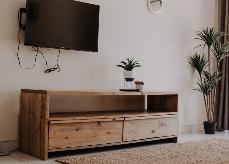 A timber TV unit and plants in an apartment lounge