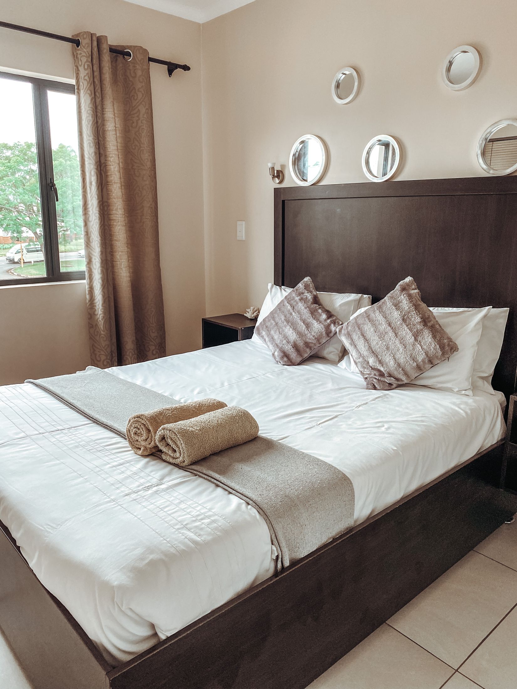 The bedroom with long curtains at the window and a made bed