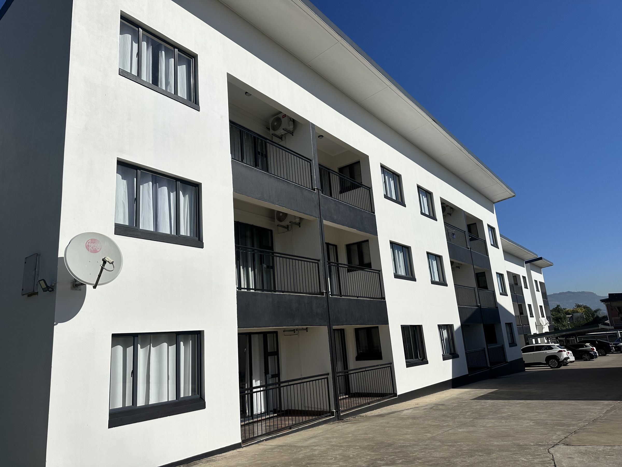 The white Wenvic apartment block with balconies on three floors, under a blue sky