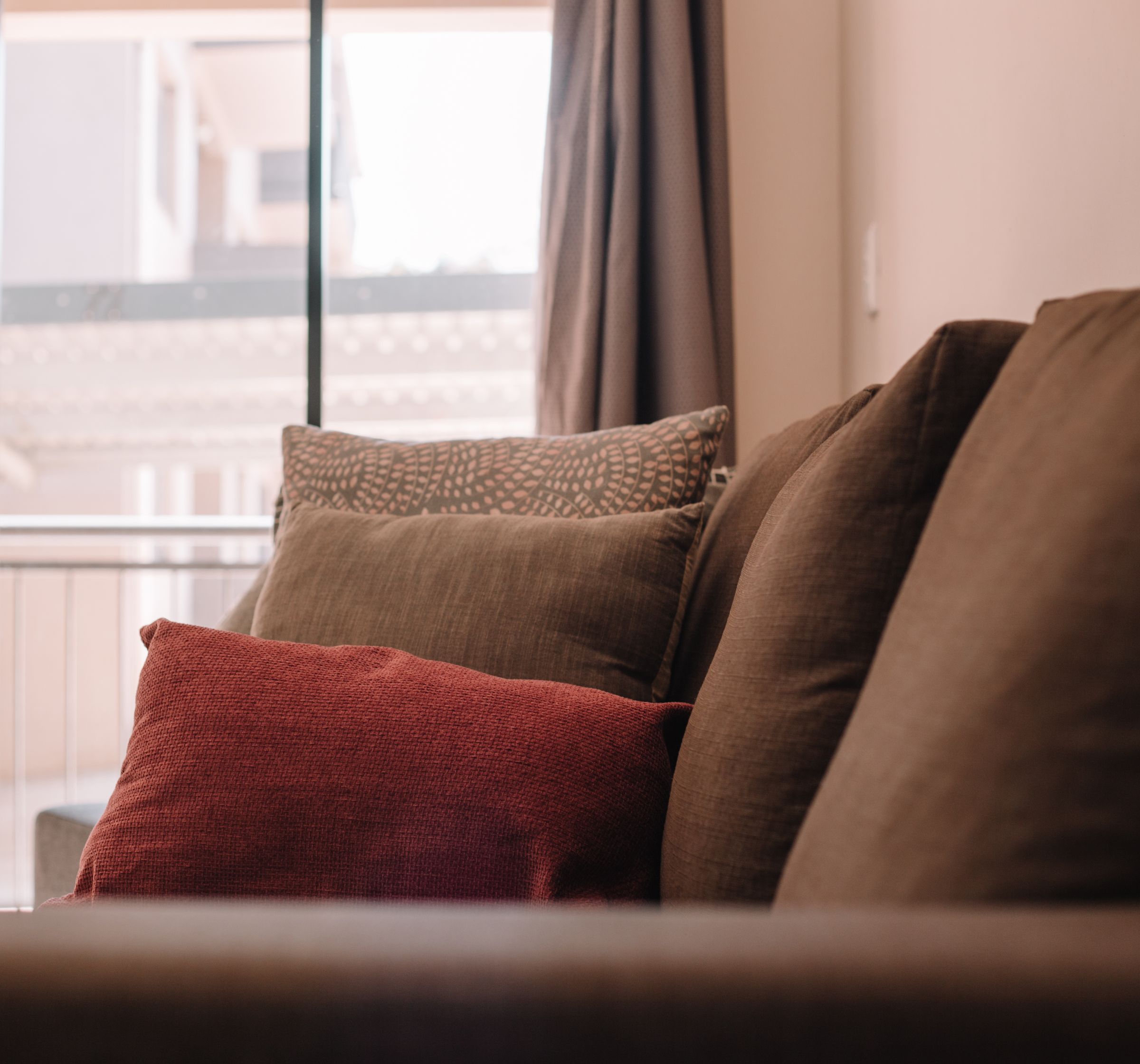 Brown and red cushions on the couch by the window