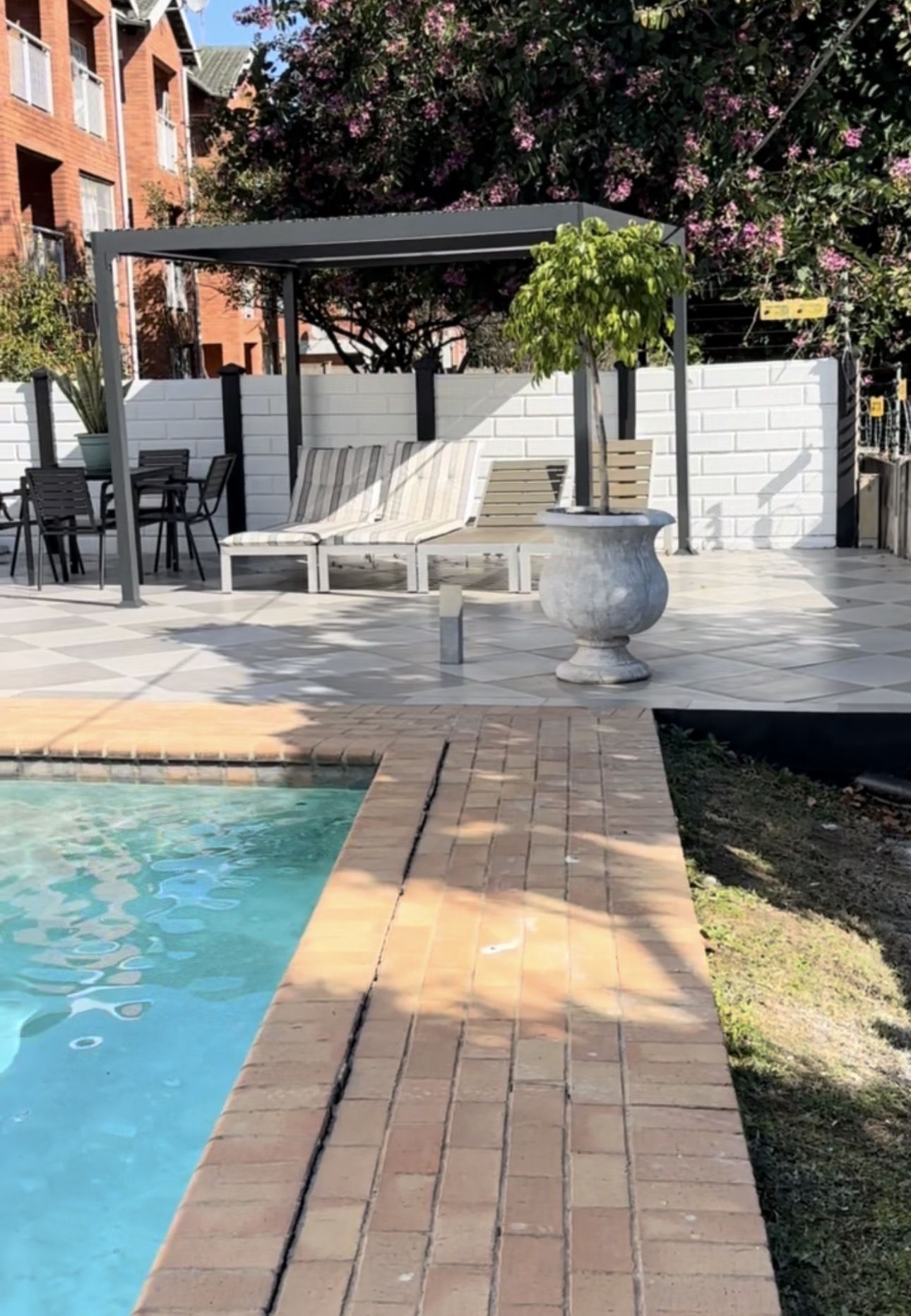 The pool with loungers and a shaded seating area