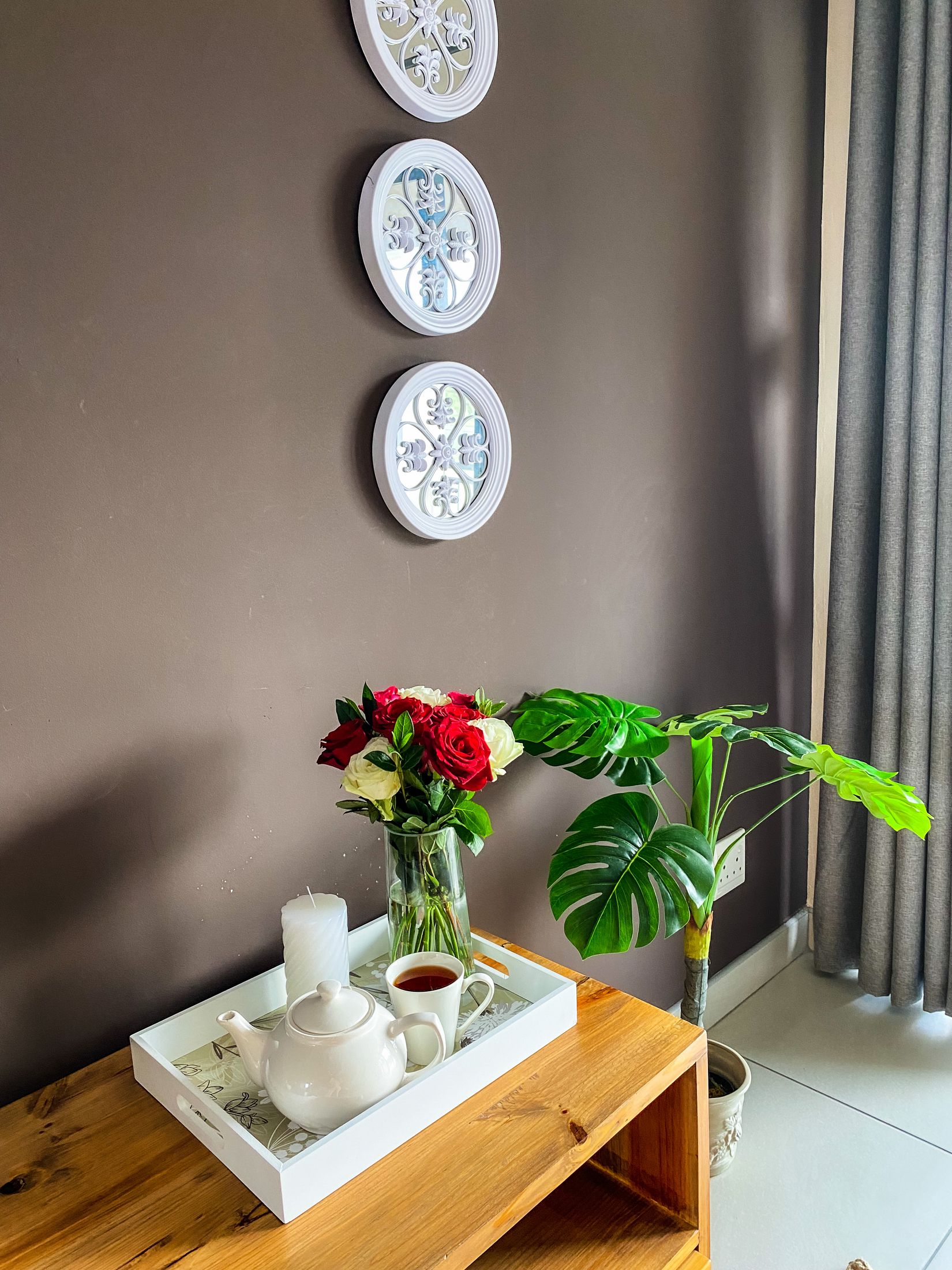 Roses and a tea tray on a timber table beside a plant
