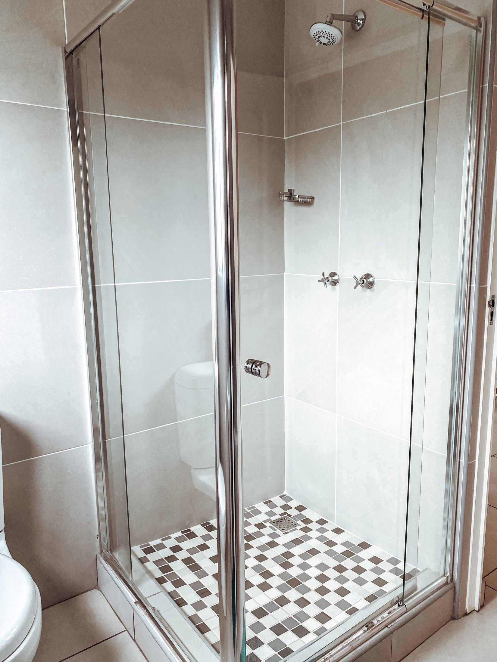 A glass shower with a mosaic tiled floor