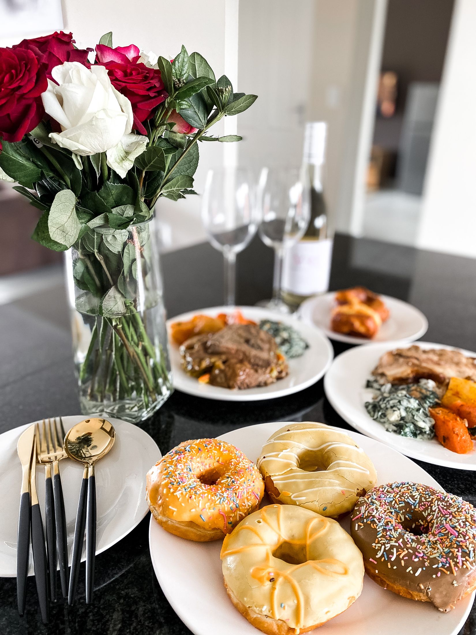 Roses, doughnuts and plates of food set out on the dining table