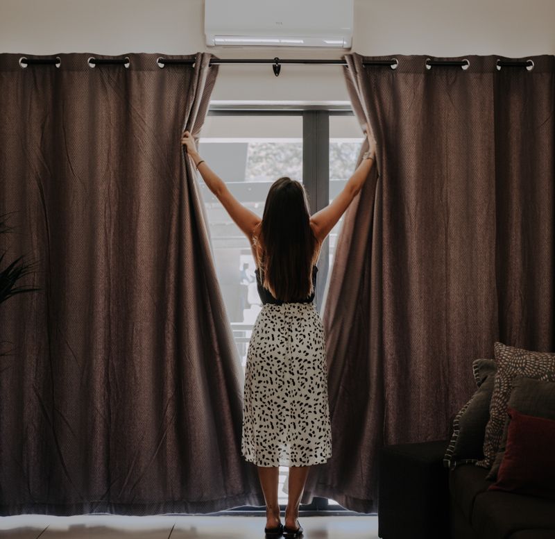 A guest opening the lounge curtains in the morning