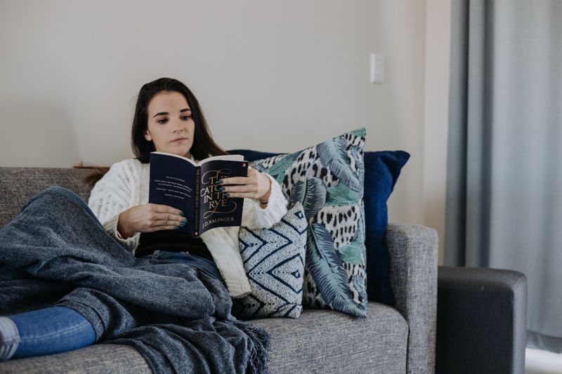 A guest reading under a blanket on the lounge couch