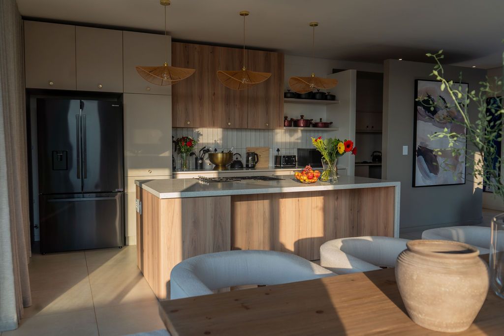 The kitchen with oak cupboards, a stone island and woven pendant lights