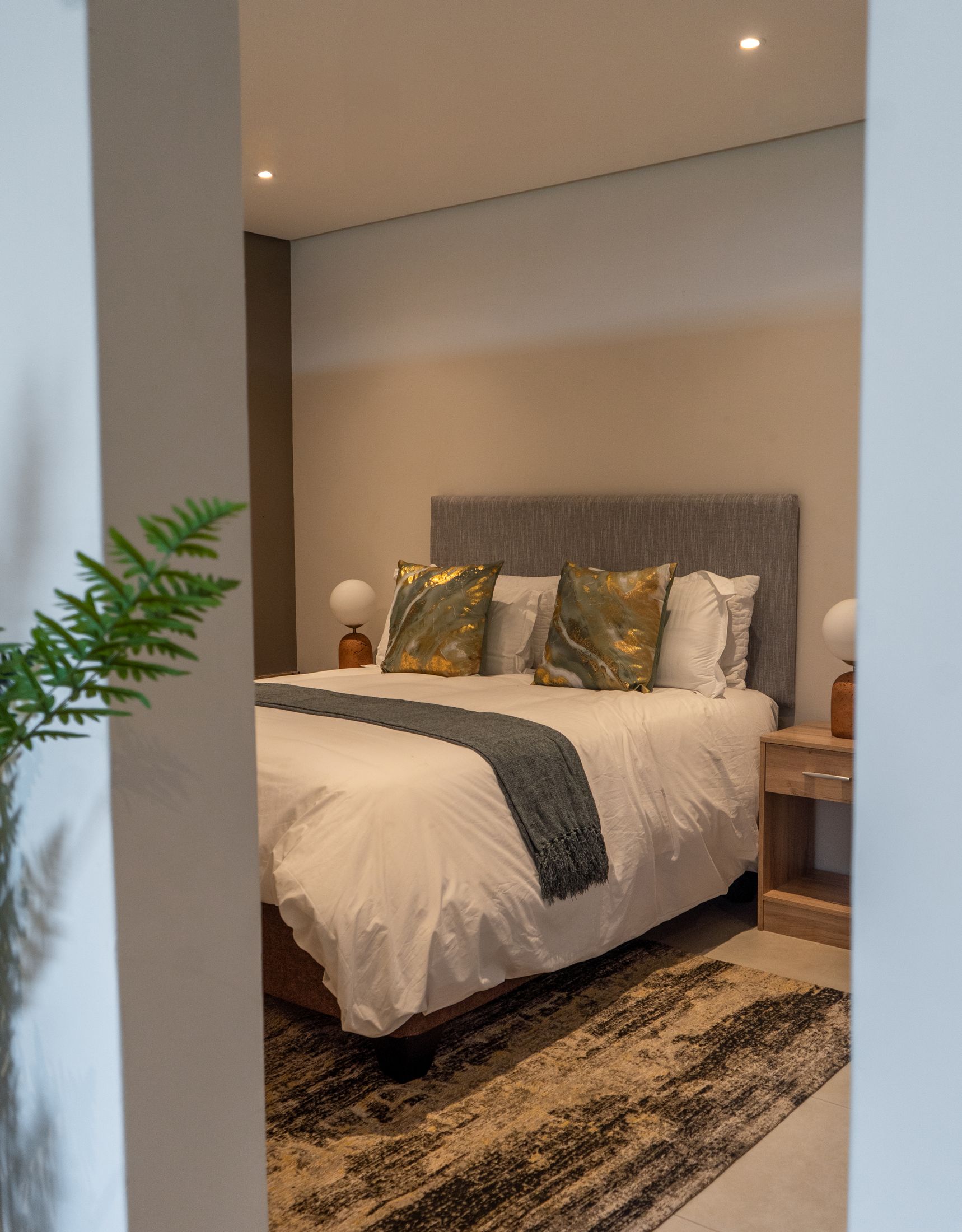 The loft bedroom with a grey headboard, gold cushions and a patterned rug