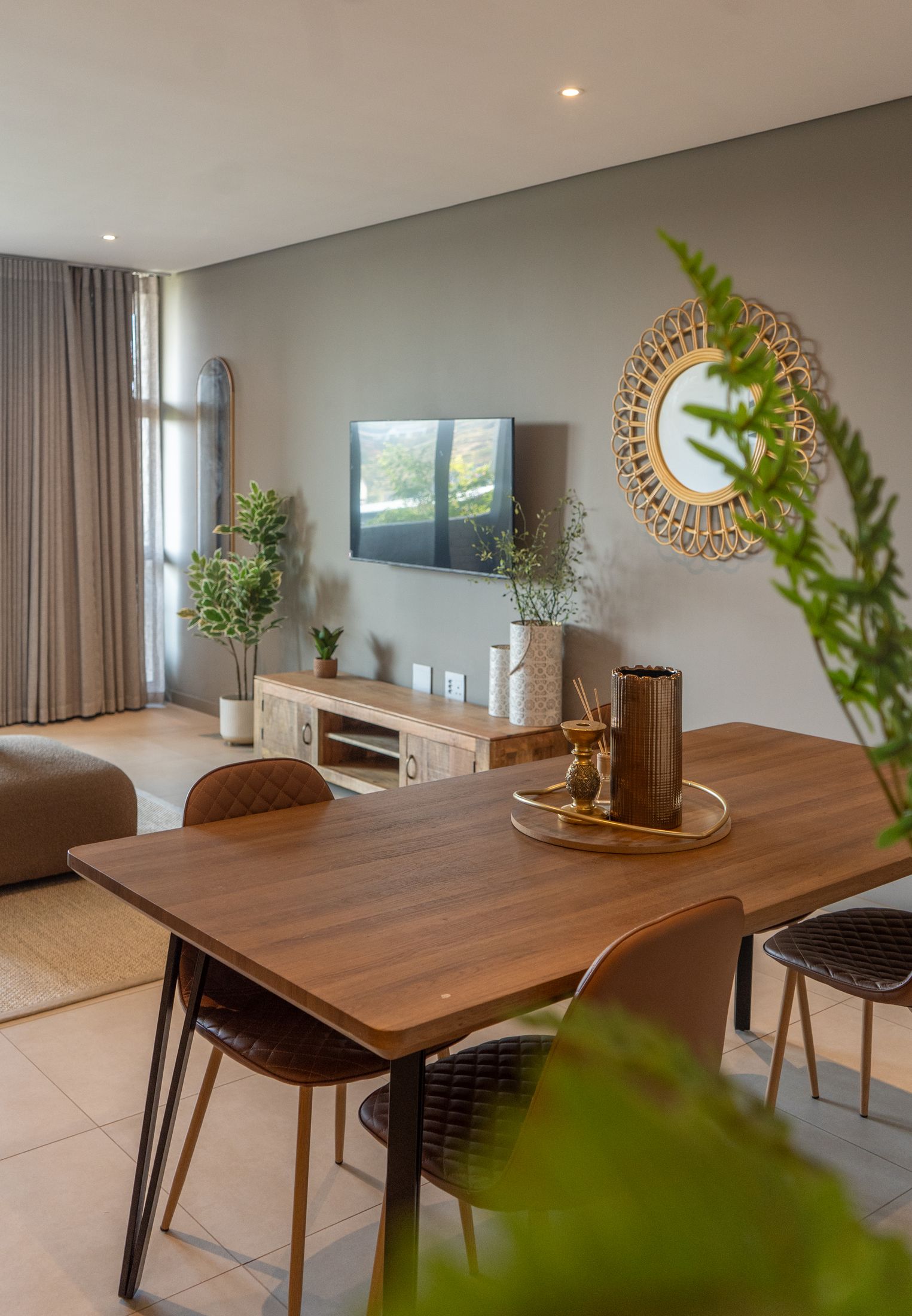 A timber dining table with brown chairs in front of the loft lounge