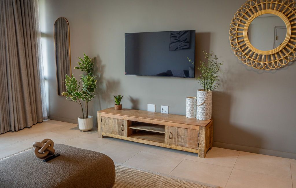 The lounge with a rattan mirror and a timber TV cabinet