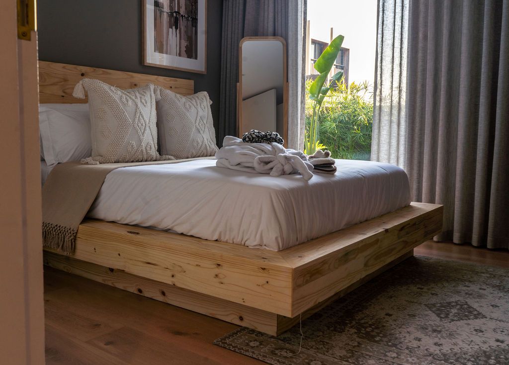 A low timber platform bed with linen cushions