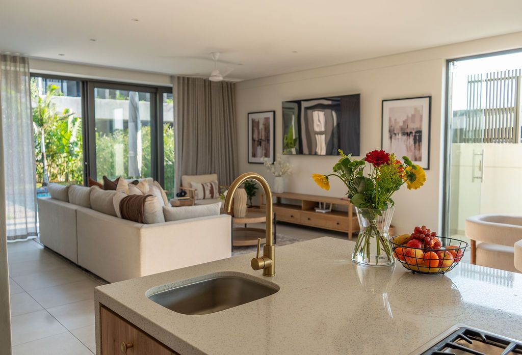 The open plan kitchen and lounge with a stone island and a brass tap